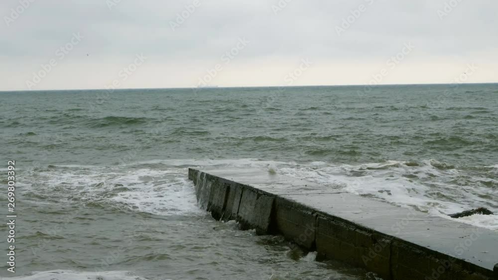 Surf at Black Sea. Small waves splits with breakwater at Black sea near Odessa. Coastline, splashing, crashing, seafoam.