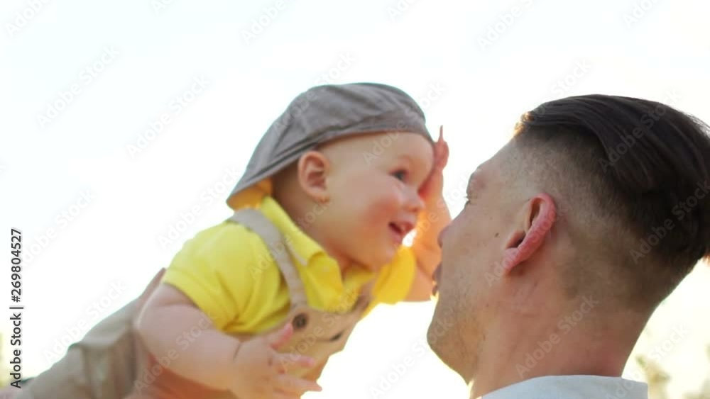 Happy young father throws up the kid upwards on sunset sky background and sunlight. Father's day, family concept Happy young father throws up the kid upwards on sunset sky background and sunlight. Father's day, family concept