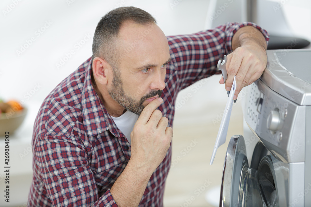 mature man reading instructions for installing a washing machine mature man reading instructions for installing a washing machine