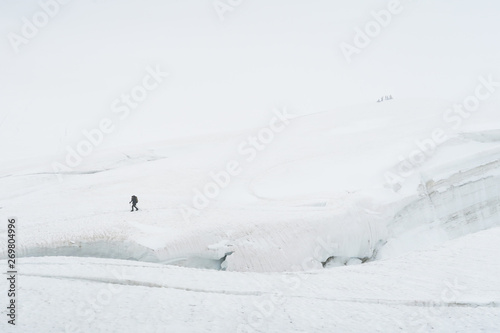 Tourist walking on the glacier near the crack. View to the Mensu glacier. Belukha Mountain area. Altai, Russia. © Olga