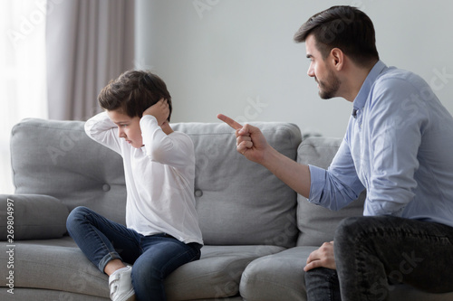 Angry dad scolding preschooler son having dispute at home photo