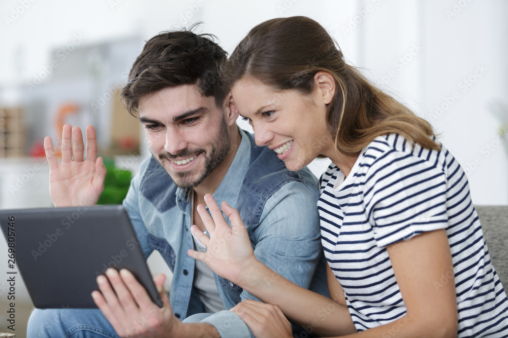 couple waving during video chat on tablet couple waving during video chat on tablet