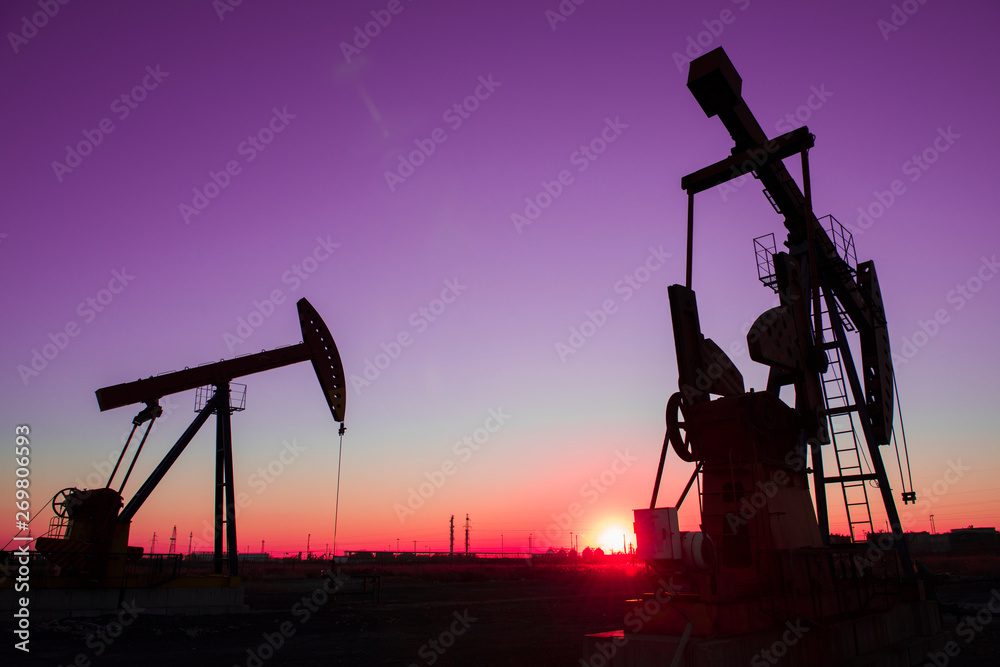 Oil pumps are running in the sunset at the oil field
