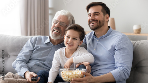 Smiling dad  son and grandfather watch TV at home