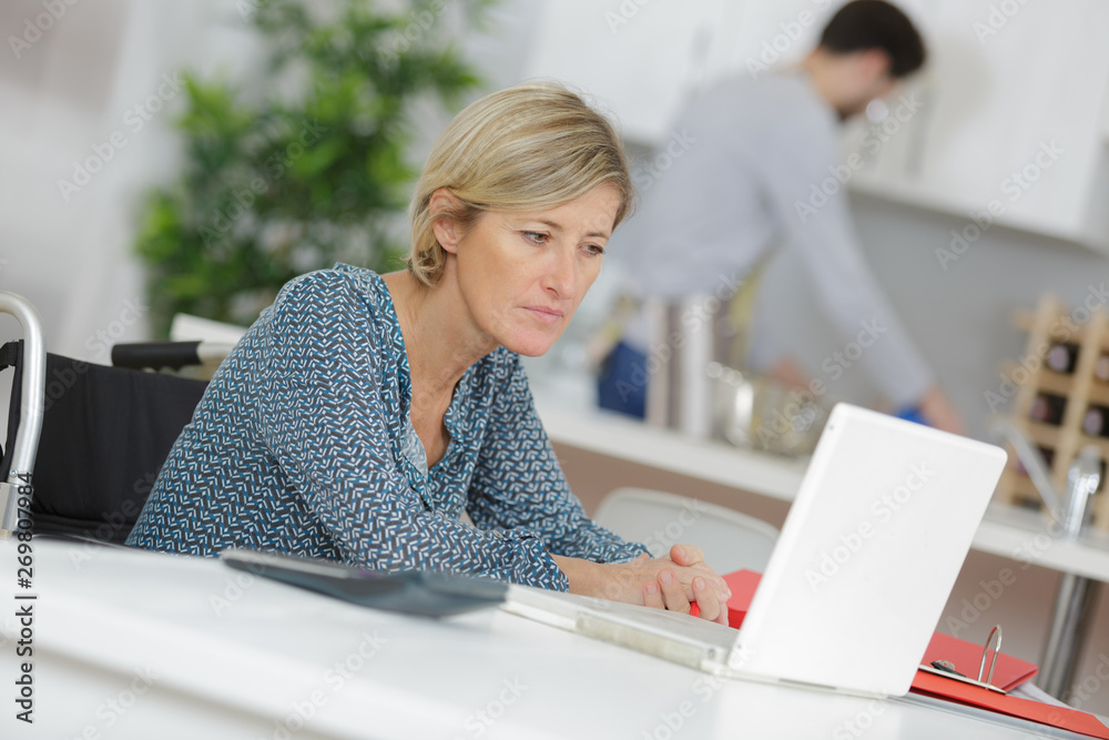disabled woman in wheelchair on laptop with purple background disabled woman in wheelchair on laptop with purple background