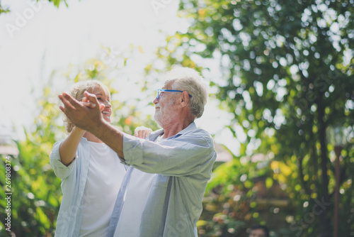 Closed up senior Caucasian couple dancing felling happy in green garden. Grand father's birthday party in summer. Big family outdoor party concept.