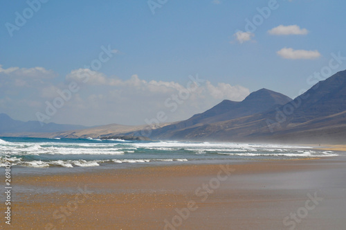 Empty sandy ocean beach on a background of mountains. Fuerteventura Canary Islands, Spain