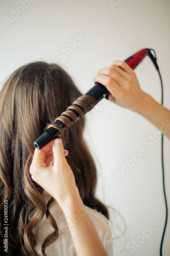 Closeup of female hands of hairdresser or coiffeur makes hairstyle