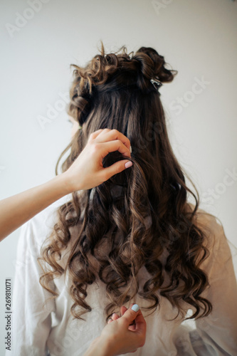 Closeup of female hands of hairdresser or coiffeur makes hairstyle