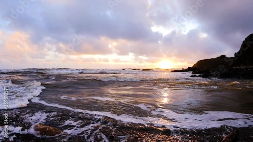 Slow motion scenic shot of beautiful california beach sunset as wave surges up coastal river, mesmerizing confluence of motion