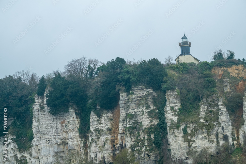 Lighthouse on a chalk cliff under a grey sky in Normandy, France
