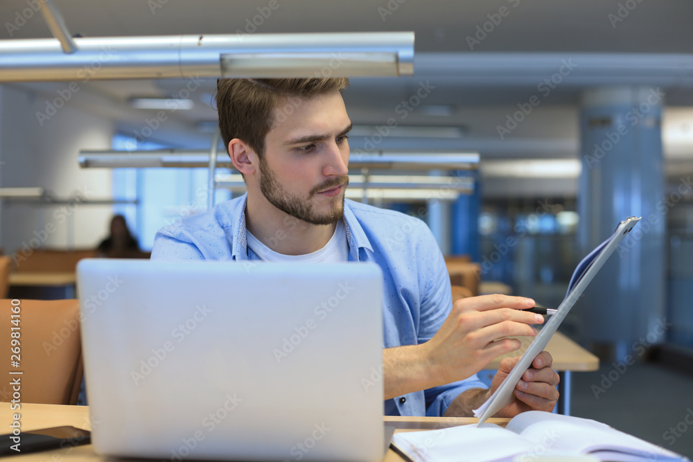 Young student working on laptop in library. Young student working on laptop in library.