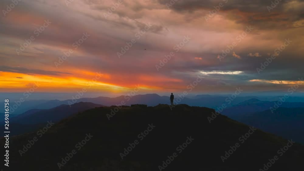 The man standing on the mountain against the beautiful sunrise The man standing on the mountain against the beautiful sunrise
