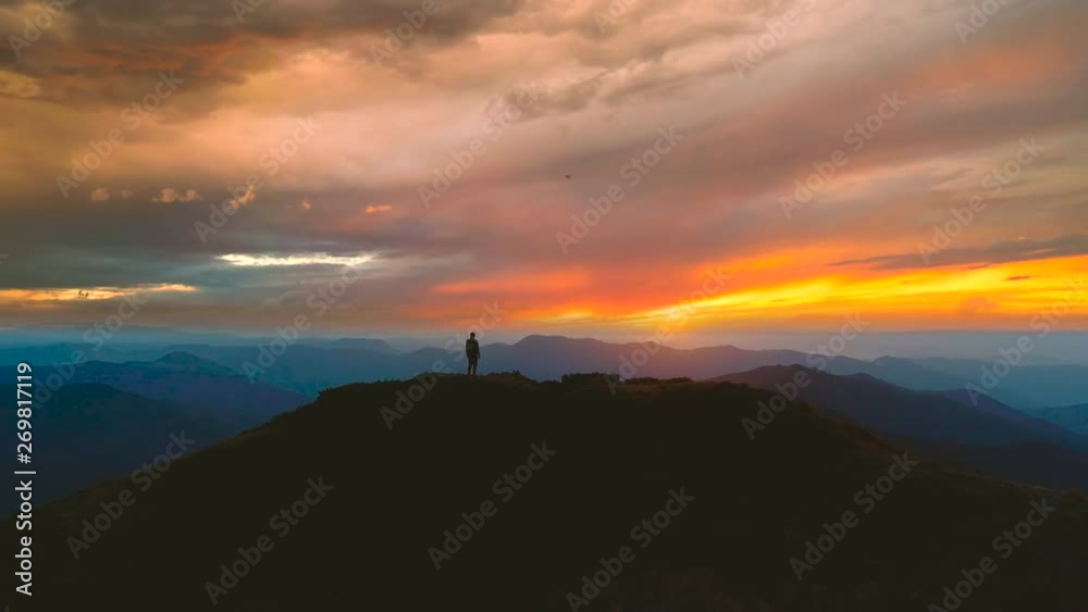 The man standing on the mountain against the beautiful sunset The man standing on the mountain against the beautiful sunset