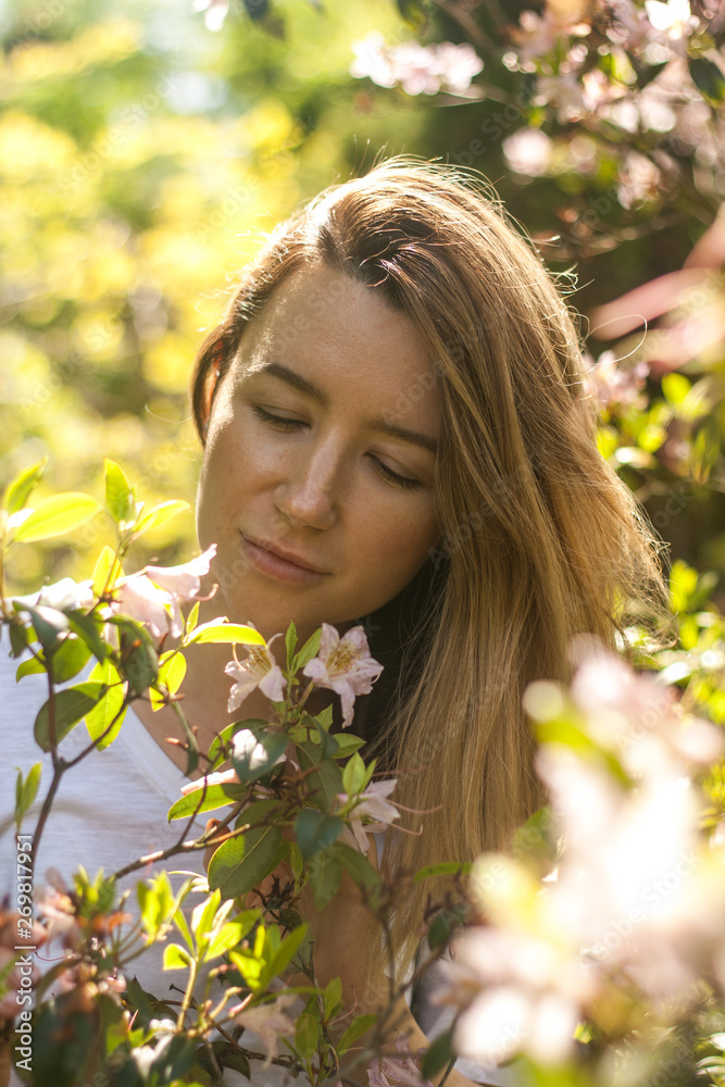 Young woman in blossoming bush in the sunny summer day
