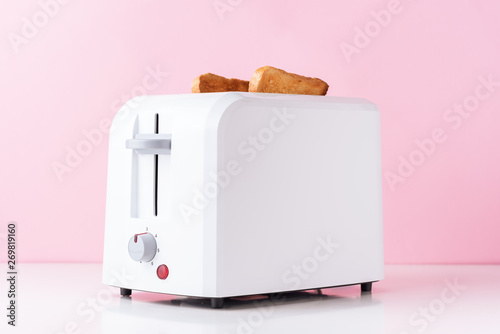 White toaster with  roasted toast bread on pink background, close up