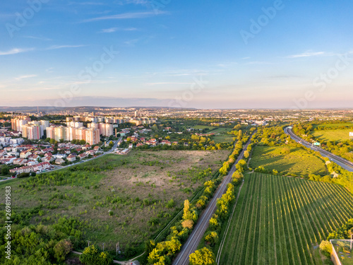 Aerial view of railway during sunset. City panorama in the background. Trees  grass and bushes in the foreground