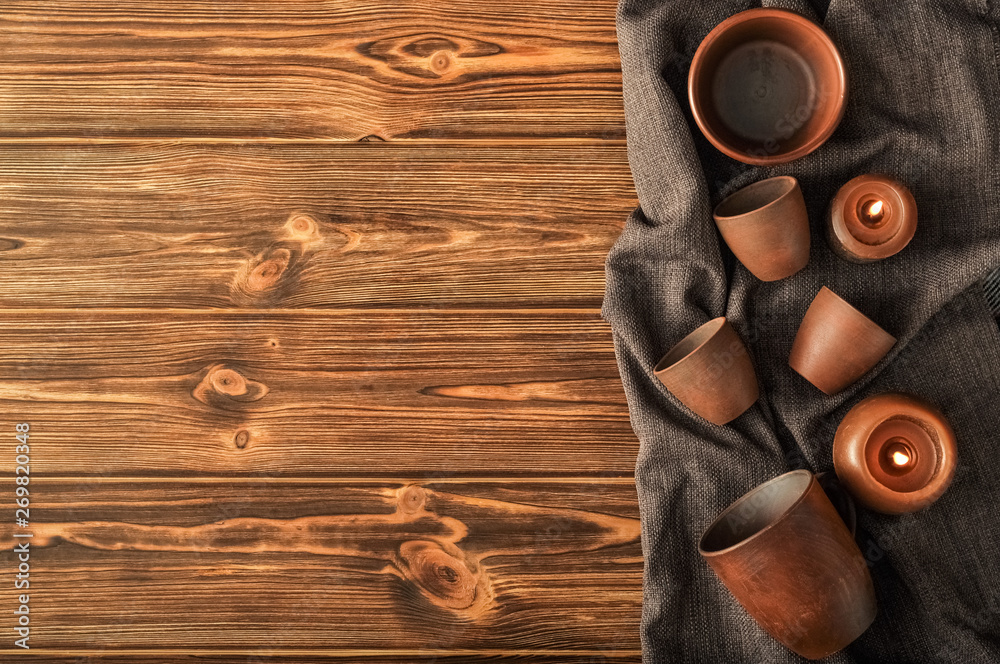 Top view set of empty rustic tableware clay, plates, cups, candles on linen on a wooden brown background Top view set of empty rustic tableware clay, plates, cups, candles on linen on a wooden brown background