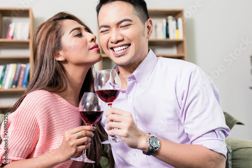 Woman kissing her boyfriend holding wineglass