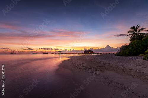Panoramic view of a sunset on a tropical beach with palm trees in the Maldives