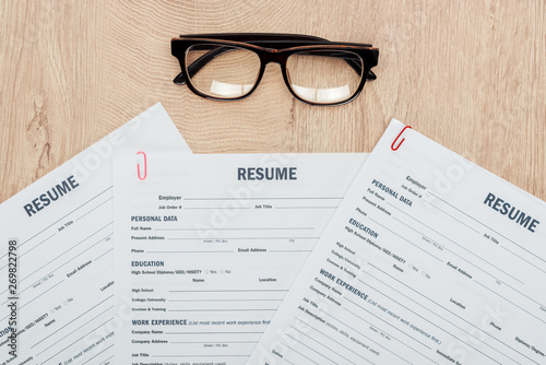 top view of print resume templates and glasses on wooden table