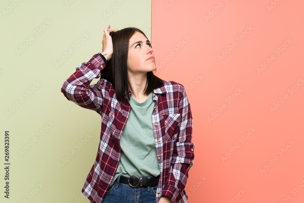 Young woman over isolated colorful wall having doubts while scratching head Young woman over isolated colorful wall having doubts while scratching head