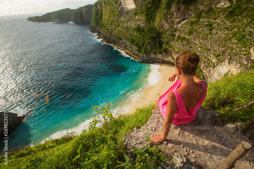  woman sitting on the edge of a cliff and looking at sunset, Nusa Penida © Maygutyak