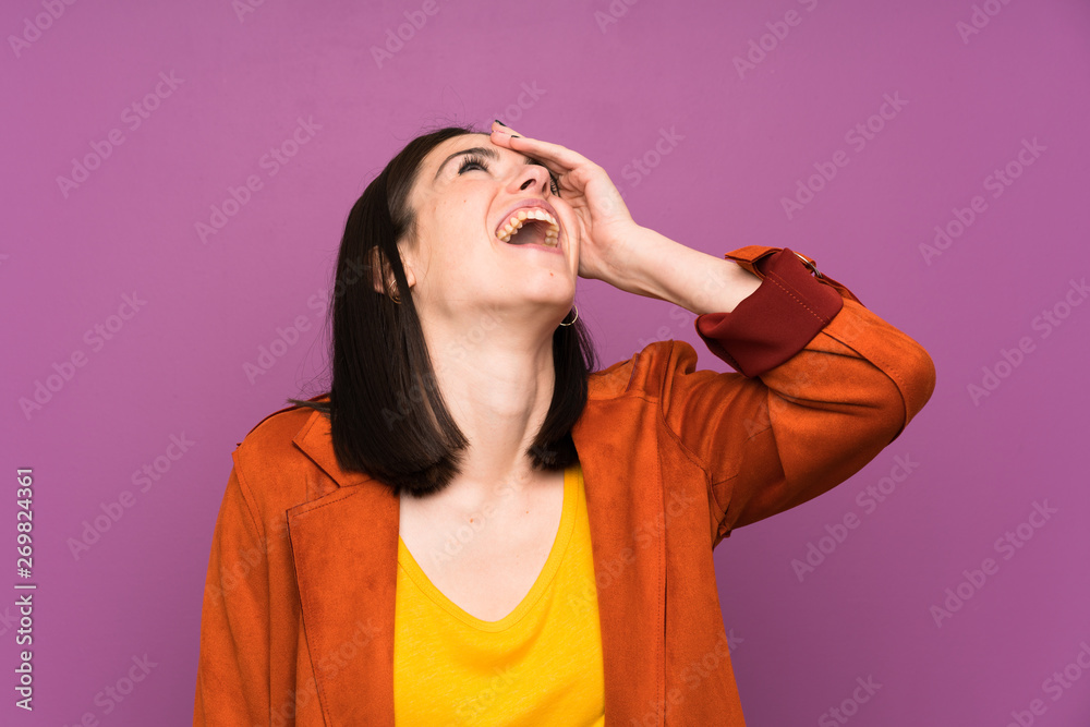 Young woman with a coat over isolated purple background laughing Young woman with a coat over isolated purple background laughing