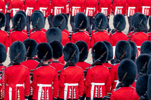 Close up of soldiers marching at the Trooping the Colour military parade at Horse Guards, London UK. Guards are wearing iconic black and red uniform and bearskin hats. photo