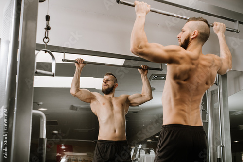 Muscular man lift his body in the gym