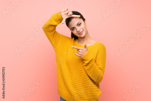 Teenager girl  over isolated pink wall focusing face. Framing symbol © luismolinero