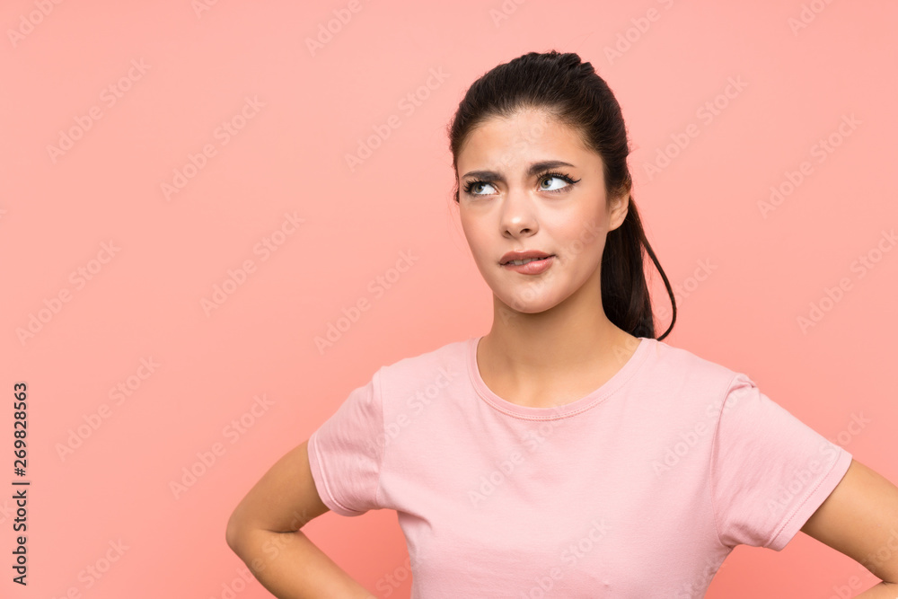 Teenager girl over isolated pink background having doubts and with confuse face expression Teenager girl over isolated pink background having doubts and with confuse face expression
