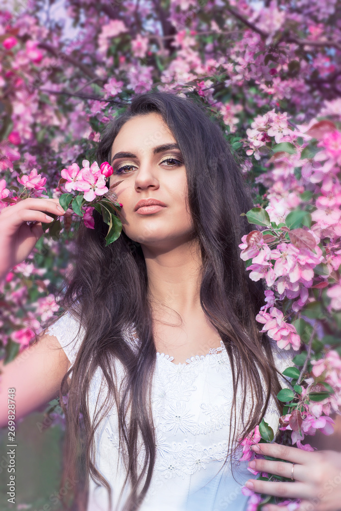 Sensual portrait of a spring woman, beautiful face, close up on blue eyes, female enjoying cherry blossom, dreamy girl with pink fresh flowers outdoor, seasonal nature, tree branch and natural beauty Sensual portrait of a spring woman, beautiful face, close up on blue eyes, female enjoying cherry blossom, dreamy girl with pink fresh flowers outdoor, seasonal nature, tree branch and natural beauty