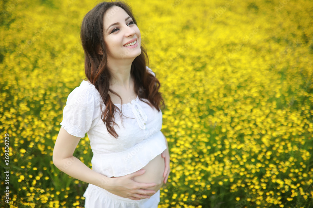 Pregnant woman in a dress in a field of flowers Pregnant woman in a dress in a field of flowers