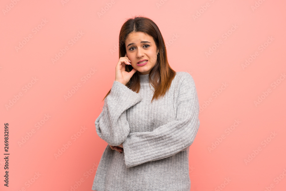 Young woman over pink wall having doubts Young woman over pink wall having doubts