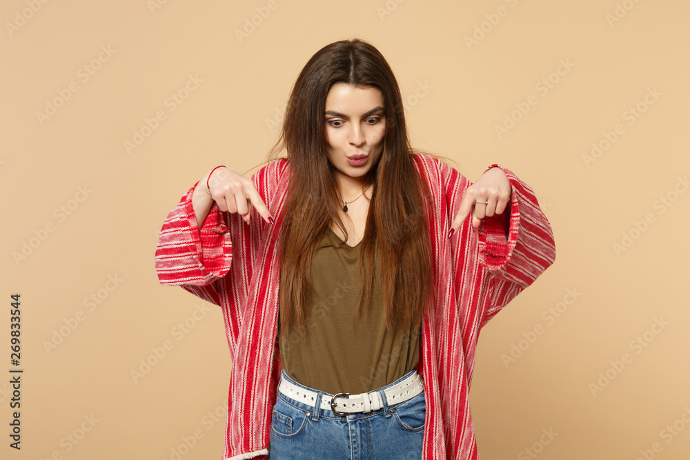 Portrait of shocked young woman in casual clothes looking, pointing index fingers down isolated on pastel beige background in studio. People sincere emotions, lifestyle concept. Mock up copy space. Portrait of shocked young woman in casual clothes looking, pointing index fingers down isolated on pastel beige background in studio. People sincere emotions, lifestyle concept. Mock up copy space.