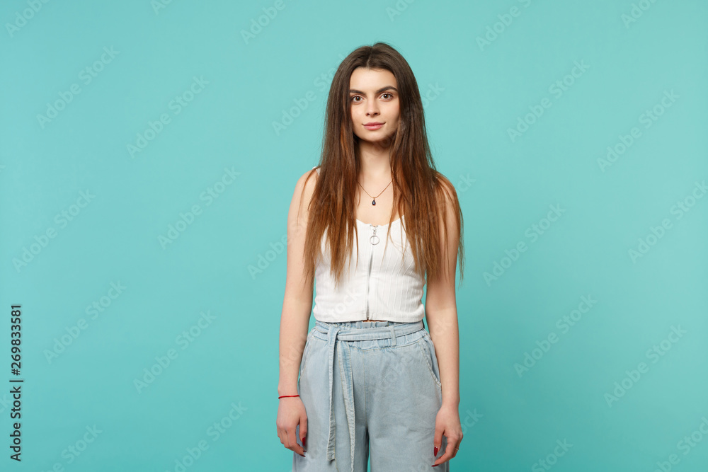 Portrait of beautiful young woman in light casual clothes standing, looking camera isolated on blue turquoise wall background in studio. People sincere emotions, lifestyle concept. Mock up copy space. Portrait of beautiful young woman in light casual clothes standing, looking camera isolated on blue turquoise wall background in studio. People sincere emotions, lifestyle concept. Mock up copy space.
