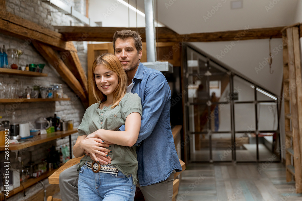 Happy young lovely couple in the kitchen hugging each other