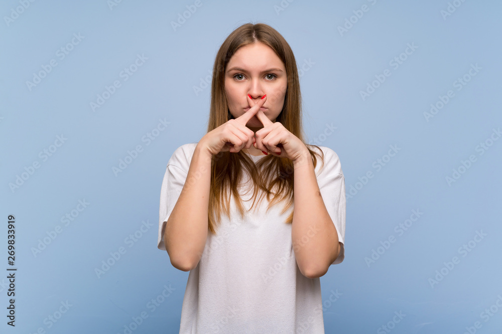 Young woman over blue wall showing a sign of silence gesture Young woman over blue wall showing a sign of silence gesture
