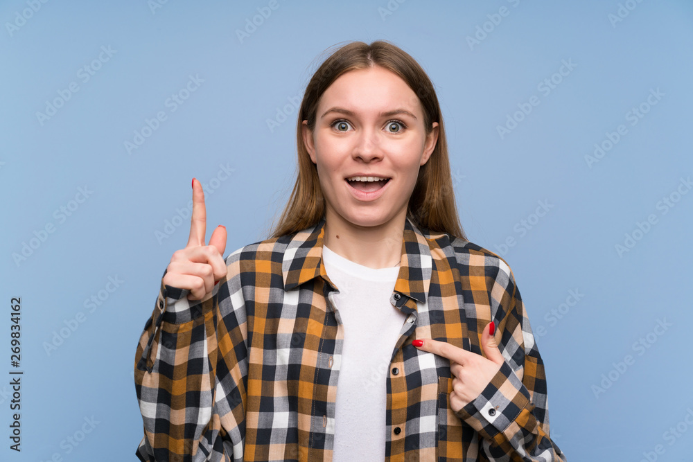 Young woman over blue wall with surprise facial expression Young woman over blue wall with surprise facial expression