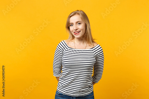 Portrait of smiling young woman in striped clothes looking camera, showing tongue isolated on yellow orange wall background in studio. People sincere emotions, lifestyle concept. Mock up copy space.