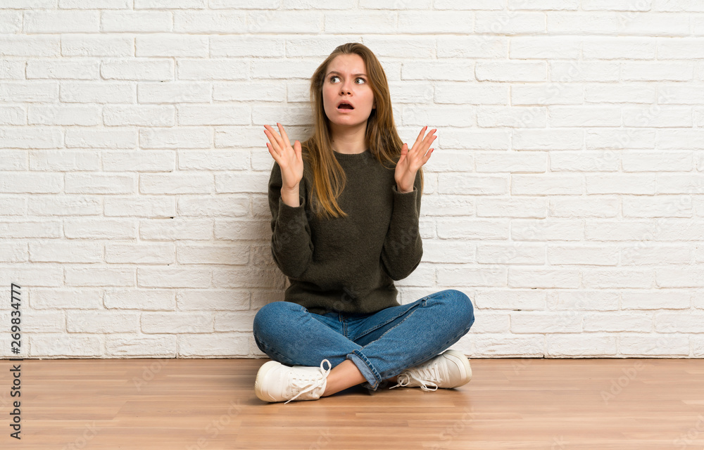 Young woman sitting on the floor frustrated by a bad situation Young woman sitting on the floor frustrated by a bad situation