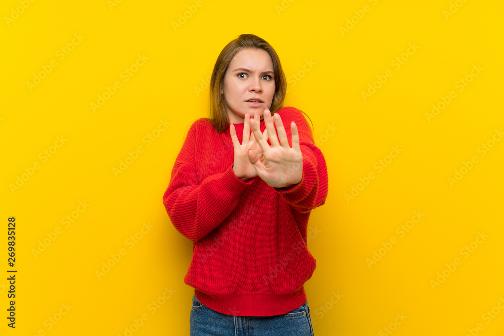 Young woman over yellow wall nervous stretching hands to the front Young woman over yellow wall nervous stretching hands to the front