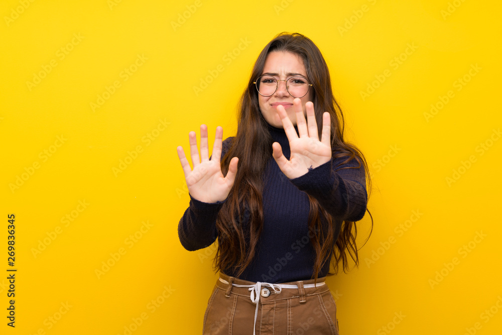 Teenager girl over isolated yellow wall nervous stretching hands to the front Teenager girl over isolated yellow wall nervous stretching hands to the front