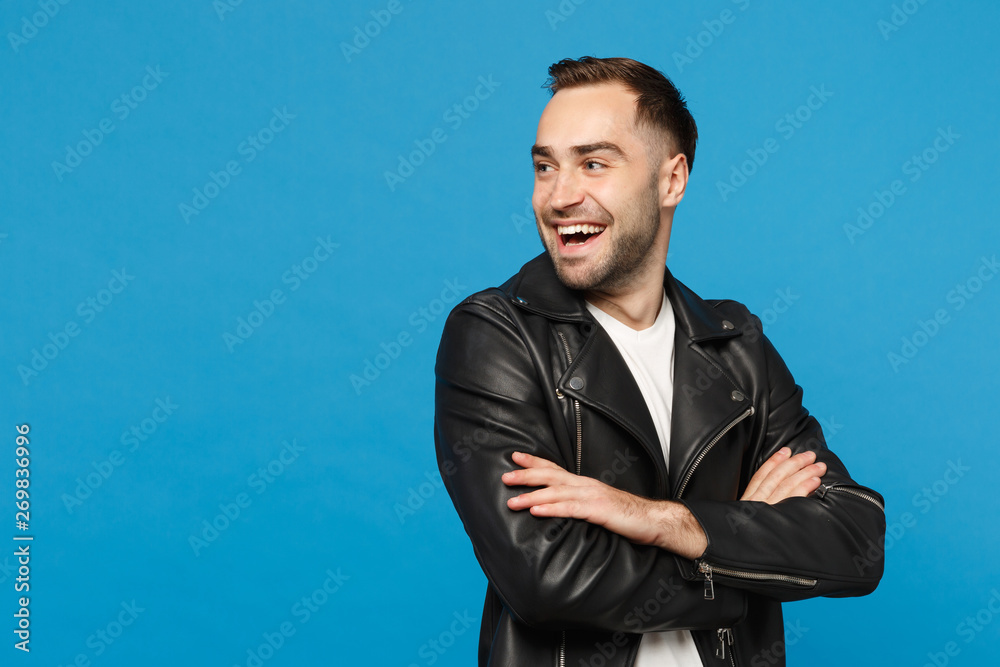 Handsome stylish young bearded man in black leather jacket white t-shirt looking aside isolated on blue wall background studio portrait. People sincere emotions lifestyle concept. Mock up copy space. Handsome stylish young bearded man in black leather jacket white t-shirt looking aside isolated on blue wall background studio portrait. People sincere emotions lifestyle concept. Mock up copy space.