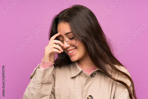 Teenager girl over purple wall laughing