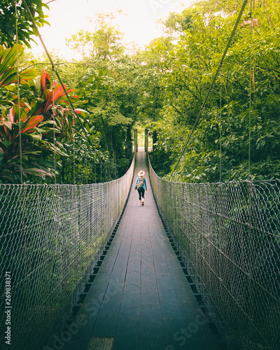 Woman walking on the bridge in the jungle of Costa Rica. photo
