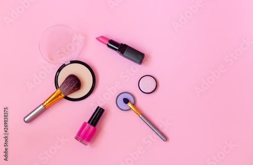 Makeup cosmetics and brushes on pink background.