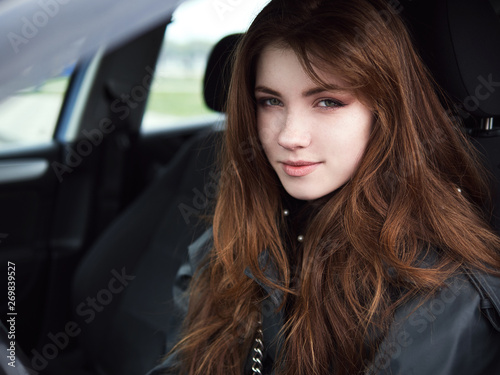 Close up portrait of young attractive red hair self-employed business woman driver sitting in white car stuck in a city traffic jam staring into camera running late to work noonday bleached colors © sergeyzapotylok