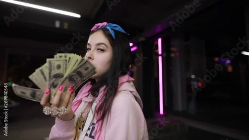 Rich girl play with dollars money at night city